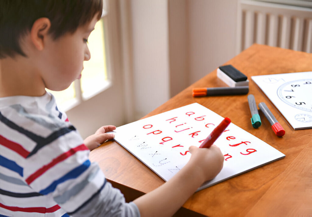 Niño aprendiendo el abecedario en inglés con rotuladores sobre un cuaderno.